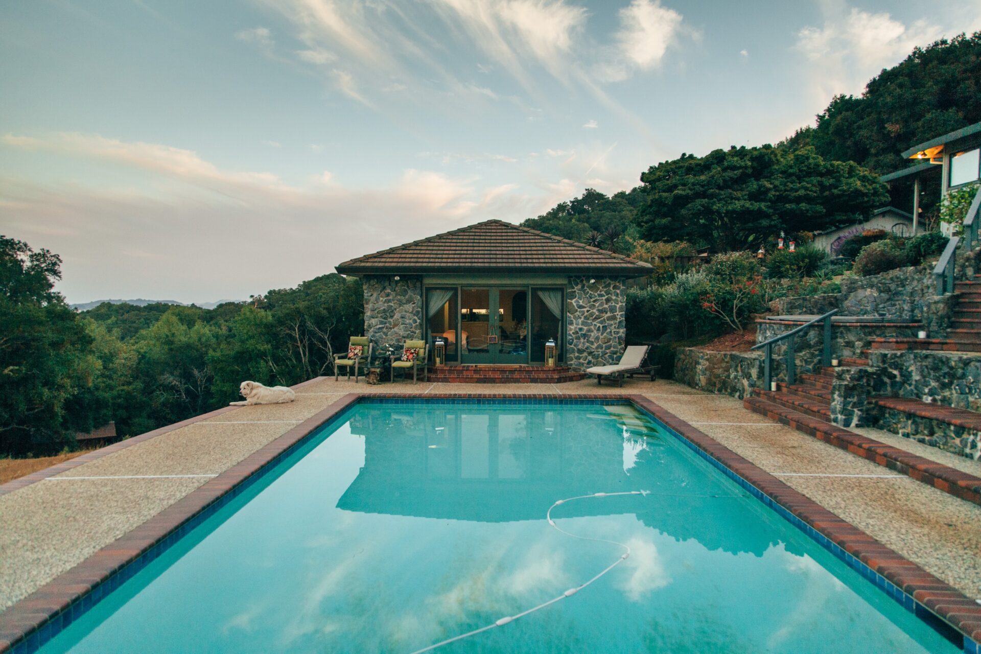 pooldeck pool with trees and a stone building in the background